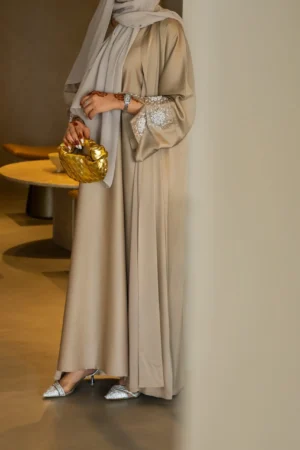 Elegant champagne abaya with intricate sleeve embellishments for a sophisticated modest fashion look.