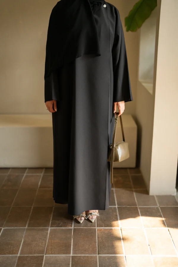 A model in a full black abaya holding a bag