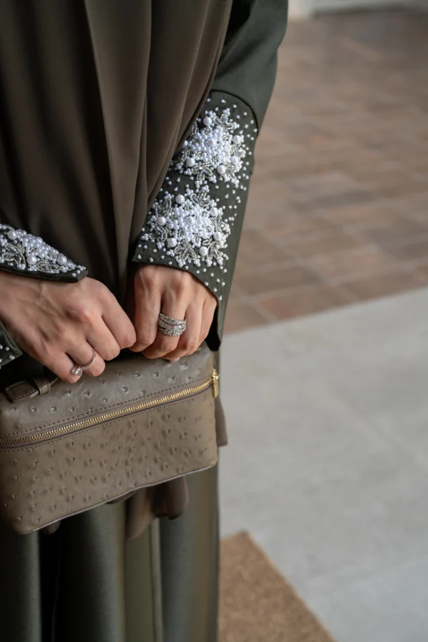 A woman modelling an olive abaya outfit by showing off the sleeve