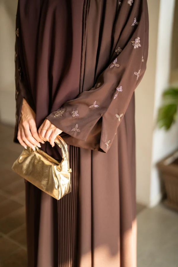 A model in coffee shade abaya with gold bag as accessory