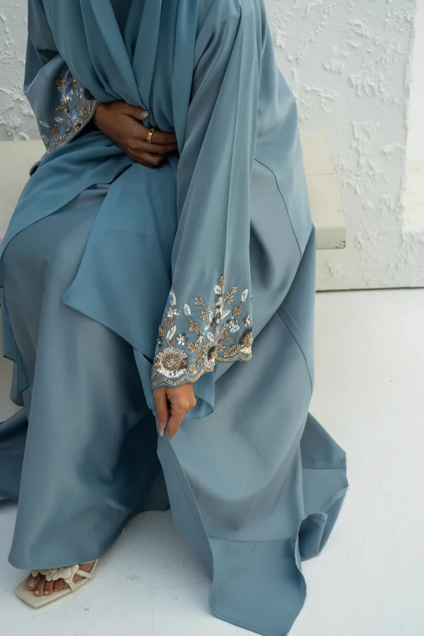 A model wearing a blue abaya with sleeve embellishment