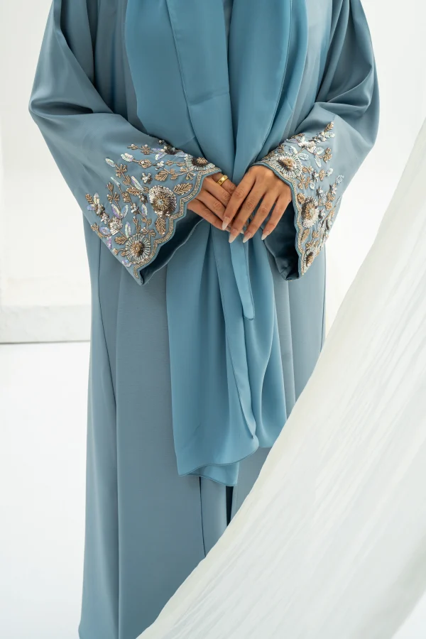 A model wearing a blue embellished abaya with matching hijab