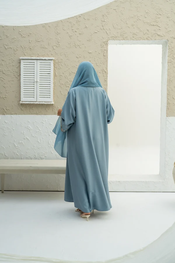 A model wearing a blue abaya with matching hijab