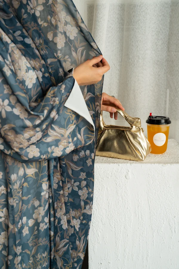 A model wearing mahra teal floral abaya with matching hijab
