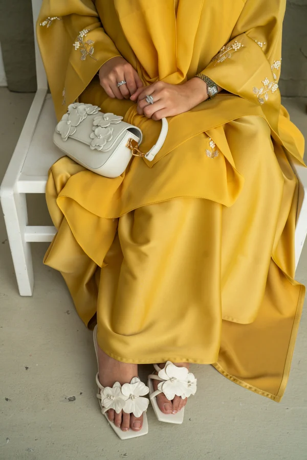 A model wearing a yellow abaya embroidery sleeve with a matching